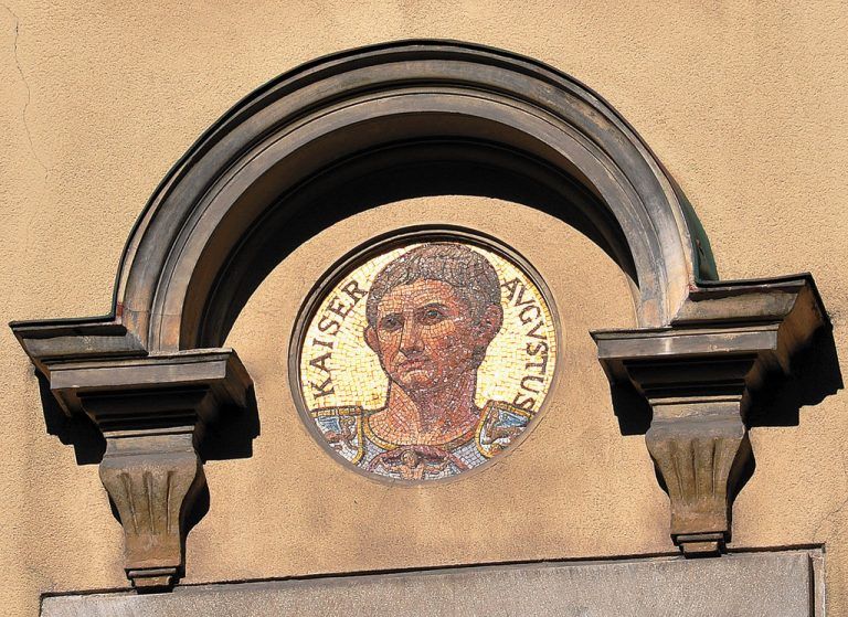 Benedikt Bilgeri hat 760 Seiten gebraucht, um die Geschichte von Bregenz aufzuschreiben. Aber es geht auch schneller. An der historistischen Fassade des Rathauses von 1898 prangen fünf Mosaike. Der Künstler Josef Boss goss seine Kurzversion in fünf Gesichter. Kaiser Augustus etwa erinnert an römische Glanzzeiten, das Bildnis Herzog Siegmunds daran, dass Bregenz 1451 zur Hälfte an das Haus Österreich ging. Maria Theresia schließlich erzählt davon, dass Bregenz 1750 Mittelpunkt der Verwaltung in Vorarlberg wurde. Foto: Andreas Praefcke