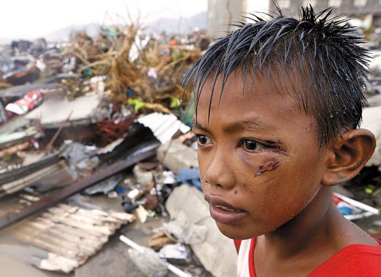 Ein Bub vor den Ruinen seines Elternhauses in Tacloban. Foto: RTS