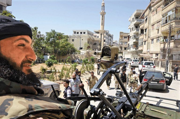 Kämpfer der Freien Syrischen Armee begleiten die UN-Chemiewaffenexperten durch einen Vorort von Damaskus. Foto: RTS