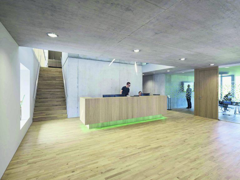 Sichtbeton, Holz und Glas dominieren die Innenräume von MIA Systems. Den Kosten geschuldet ist die Innendämmung bzw. Verkleidung mit weißen Gipskartonplatten der betonierten Außenwände.