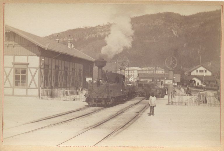Zwei hohe Säulen tragen große Räder, über die starke Ketten laufen, um die Trajektbrücke zu heben.