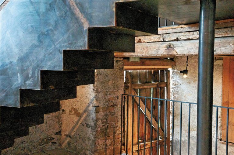 Das rohe Wellblech, das für die beiden Treppen und einen Steg verwendet wurde, ist Kontrastmaterial im sonst von Holz und Mauerwerk bestimmten Raum.