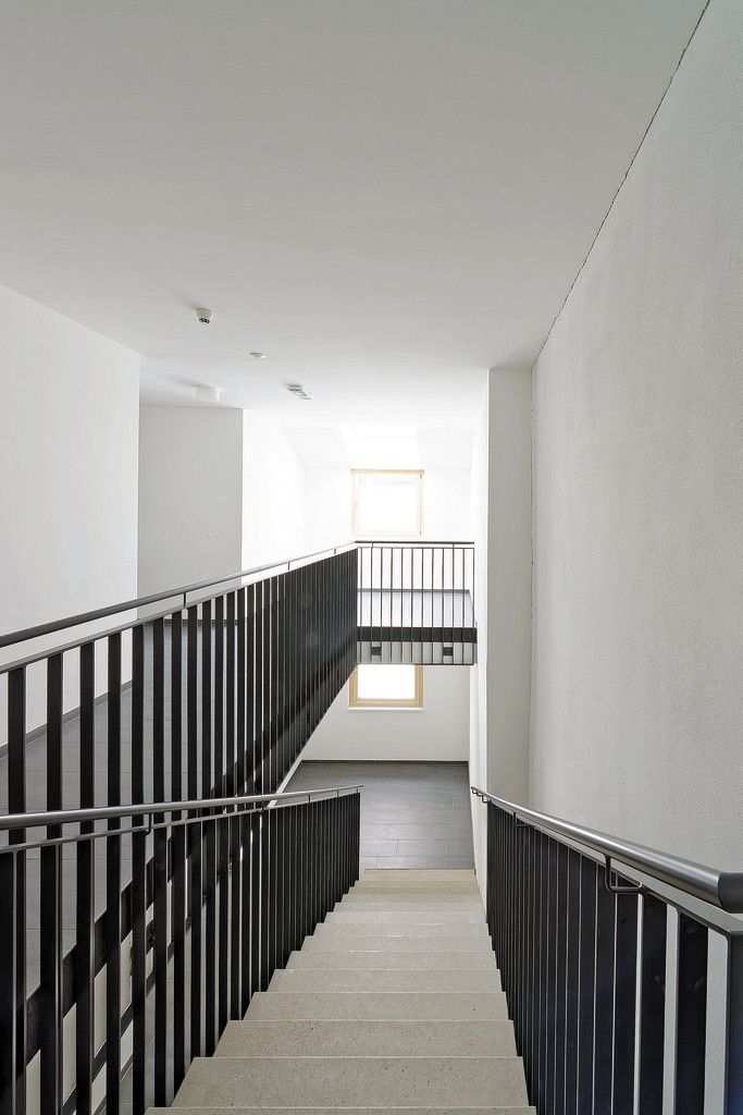Das Stiegenhaus im neuen Trakt des Schlossbräu ist funktionell schnörkellos. Die Treppen sind aus Sichtbeton, die Böden mit grauem Feinsteinzeug gelegt, die Wände weiß, die Geländer aus dunkelgrau beschichtetem Metall.