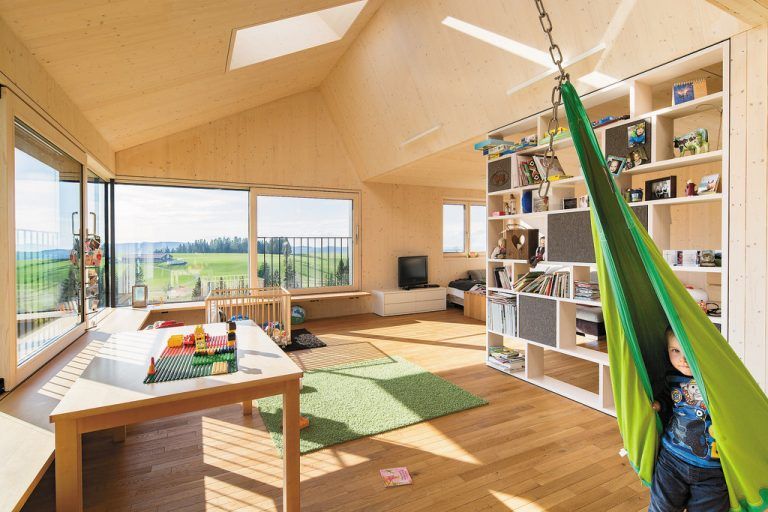 Bei uns spielt sich das ganze Leben in der Wohnküche ab: Eigentlich war im verglasten Süd-westeck eine Loggia geplant, nun erobern sich die Kinder den Raum mit Bergpanorama.