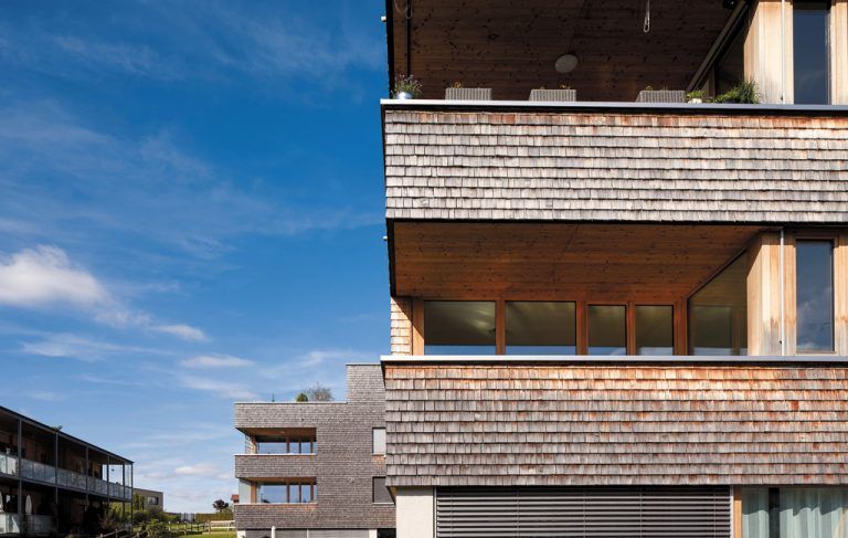 Tradierte Behaglichkeit In den Gebäudeecken sind tiefe Loggien eingeschnitten. Decke, Boden und Wand sind aus Holz, gemütlich wie ein Schopf an einem alten Wälder Bauernhaus.