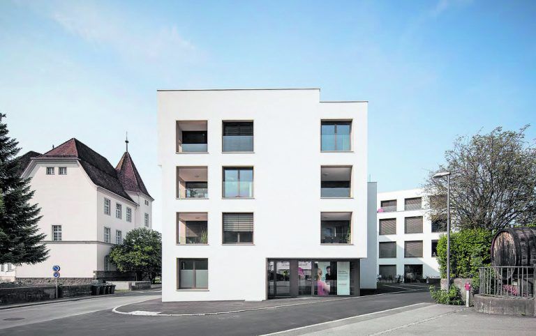 Der Eingang des größeren, direkt an der Schillerstraße stehenden Hauses ist markant aus dem Baukörper herausgeschnitten und mit braunem einbrennlackiertem Blech verkleidet.