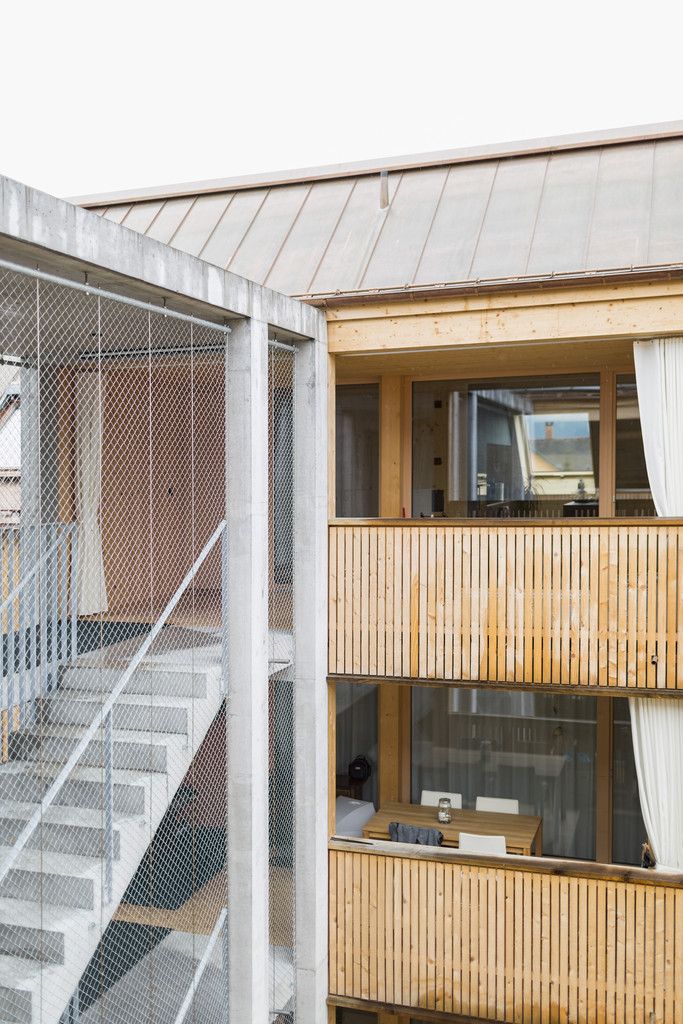 Der Materialwechsel von Beton zu Holz betont den Übergang von öffentlich zu privat. Die raumhohe Verglasung erlaubt tiefe Ein- und Durchblicke: Man sieht, wer kommt und geht.