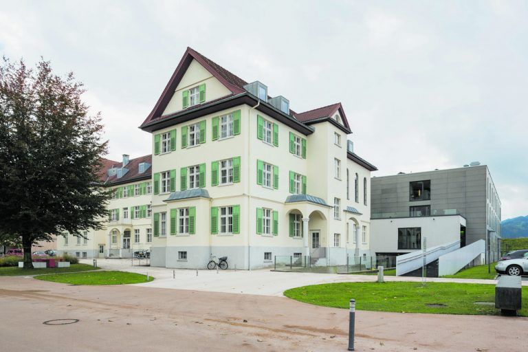 Der Z-förmige Altbau beherbergt heute in seinem Nordflügel die Räumlichkeiten für das Rote Kreuz. Rechts davon führt eine Abfahrt zur Anlieferung und eine lange Rampe zum Eingang des Pflegeheims. Links davon befindet sich der Vorplatz zum Haupteingang.