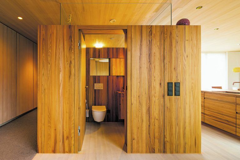 Die Garderobe entpuppt sich als Seitenwand eines Raummöbels: Es enthält die Gästetoilette, bildet die Rückwand der Küche und verbirgt gekonnt einen Hausarbeitsraum.