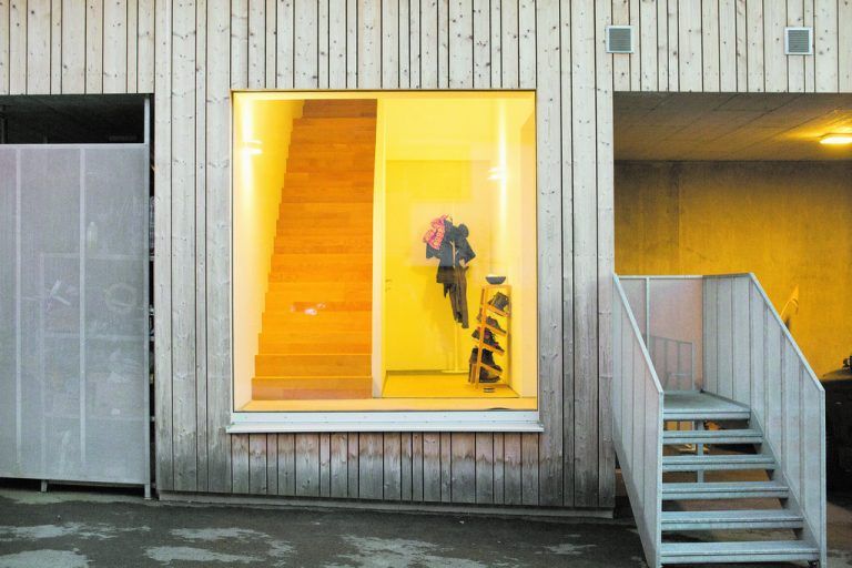 Die großen Fenster schaffen eine freundliche und halböffentliche Stimmung in den Eingangsbereichen und gleichen die unterkühlte Atmosphäre von verzinktem Lochgitter und Sichtbeton aus.