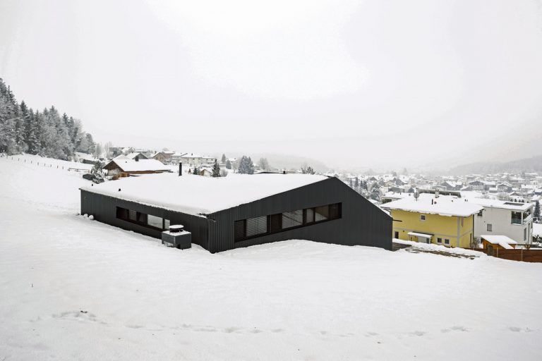 Draufsicht Sogar von der Hangseite aus sieht dieses Haus sehr elegant aus. Sein Dach ist aus demselben Material wie die Wände: schwarz beschichtetes Stahlblech.