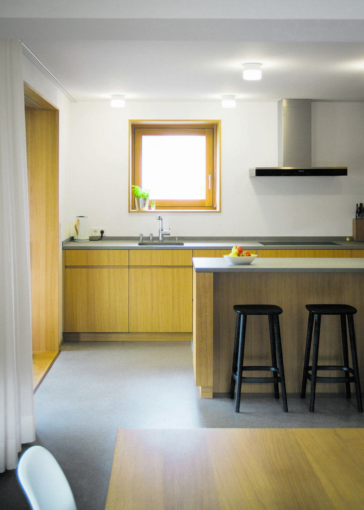 Dreifache Vergößerung einer Küche: Die Wand zum Esszimmer wurde herausgebrochen, der Grillplatz auf der Terrasse ist nur eine Glasschiebetür entfernt, und Elektrogeräte wurden in der Wand zum Eingang versenkt.