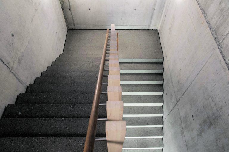 Eine zweiläufige Treppe verbindet die Räume im Erdgeschoß mit dem Großraumbüro im ersten Obergeschoß.