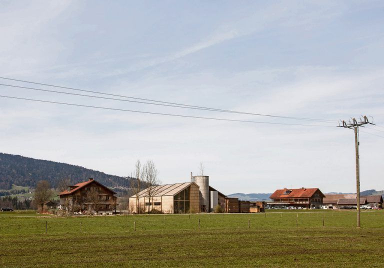 Einfügen Das Gebäude passt ins Andelsbucher Siedlungsbild, ohne sich als Wohnhaus oder Stadel zu verkleiden. Es gehört der Form und dem Material nach dazu und bleibt doch eigenständig. Die Funktion wird nicht versteckt: Es ist ein moderner Produktionsbetrieb.