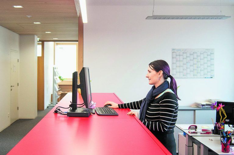 Einladend offen ist der Empfang in den Räumen der Arbeiterkammer im ersten Obergeschoß. Die Theke ist in einem fröhlichen Rot gehalten, während die Wände weiß, die Türen und Decken aus hellem Holz und die Böden grau sind.