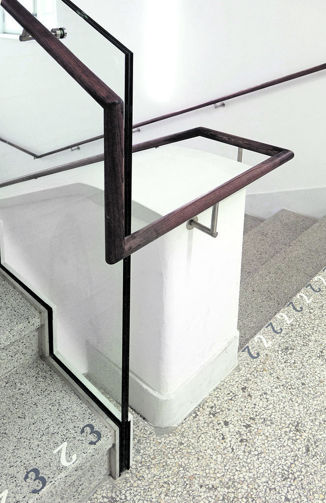 Im Stiegenhaus vereinen sich feine Architekturdetails von Willi Braun mit dem handwerklich präzisen Handlauf von Christian Lenz und einer künstlerisch gestalteten Stockwerks-anzeige von Roland Schuster.