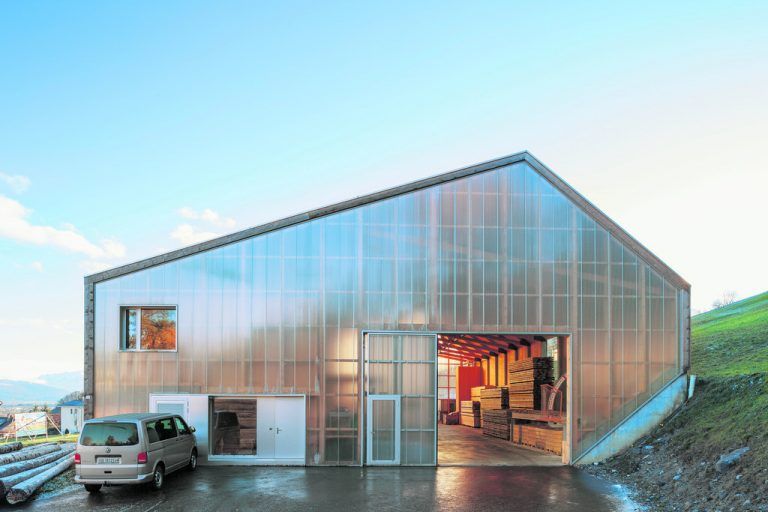Lichtdurchlässige Stegplatten verkleiden die Stirnseiten der größeren Halle. Schiebetore im selben Material öffnen sich auf beiden Seiten. Und ermöglichen so minimalste Produktionswege.