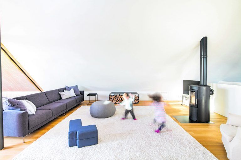 Loftartig ist auch die Couch. Ein Schwedenofen schafft einen zarten Ankerpunkt im Raum.