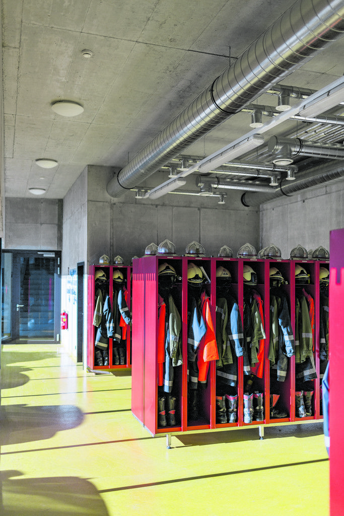 Roh und authentisch sind die dem Berg abgerungenen Räume für Garderobe und Technik; Feuerwehrrot, Betongrau und Epoxigelb im Einklang.
