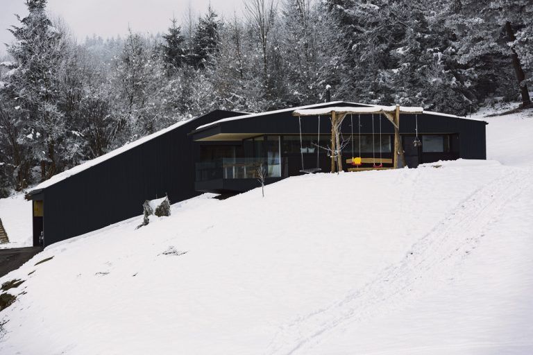 Sonnenseite Der südöstliche Flügel des Hauses ist zum Kochen, Wohnen und Essen da: eine umlaufende Terrasse umgibt diesen Wohnbereich, auf der Wiese an der Sonne steht eine Schaukel für das Kind.