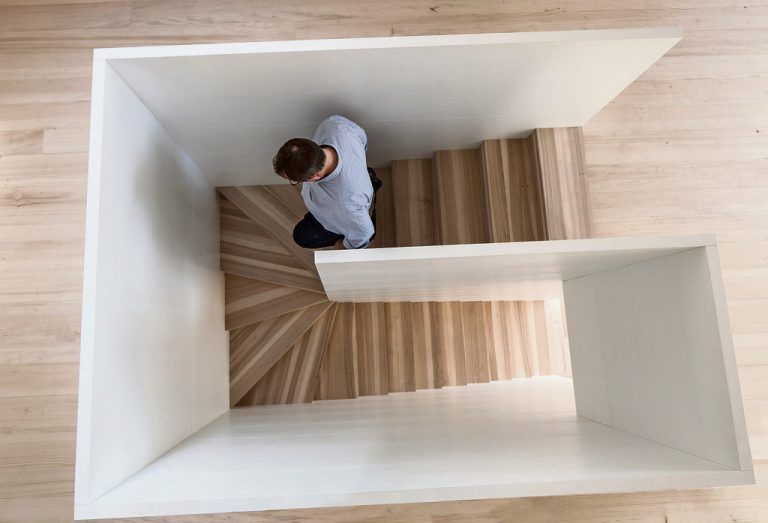 Weiß beschichtete Holzplatten für Decken und Brüstungen ergänzendie holzsichtigen Bauteile. Büro und Schauraum sind über eine Treppe aus Eschenholz verbunden.