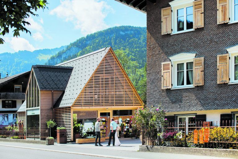 zwischen dem Neubau und dem alten Wohnhaus ist ein einladender Platz entstanden. Er wird als Ausstellungsfläche genutzt, man kann auch auf einer Holzbank sitzen und die Buntheit genießen.