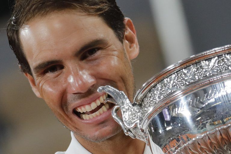 Spain's Rafael Nadal bites the trophy as he celebrates winning the final match of the French Open tennis tournament against Serbia's Novak Djokovic in three sets, 6-0, 6-2, 7-5, at the Roland Garros stadium in Paris, France, Sunday, Oct. 11, 2020. (AP Photo/Christophe Ena)