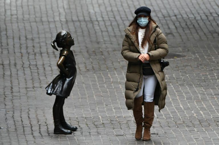 Eine Passantin spaziert an der Bronzestatue 
