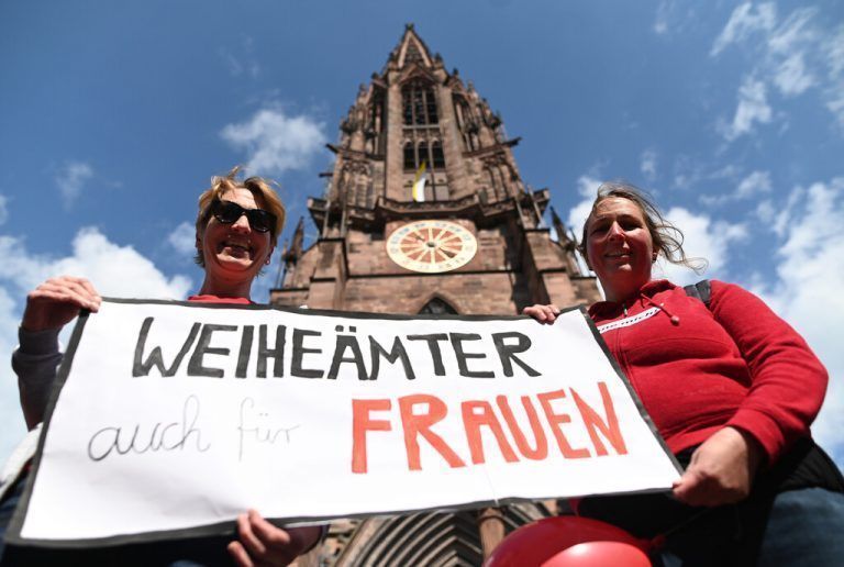 Zwei Frauen der Initiative Maria 2.0 in der Erzdiözese Freiburg halten vor dem Münster ein Banner mit der Aufschrift „Weiheämter auch für Frauen“. APA
