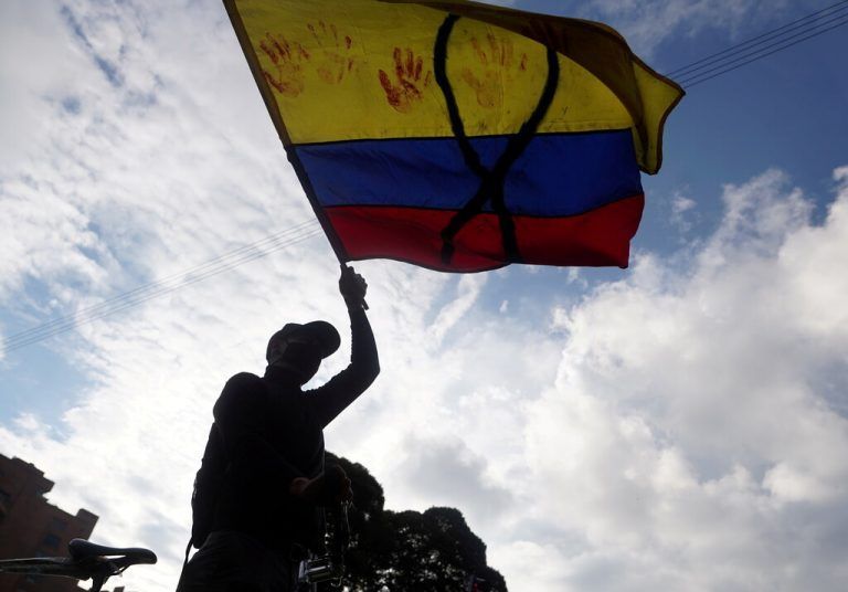 Bei einem Protest gegen Armut und Polizeigewalt in Bogotá schwenkt ein Demonstrant eine kolumbianische Fahne. reuters