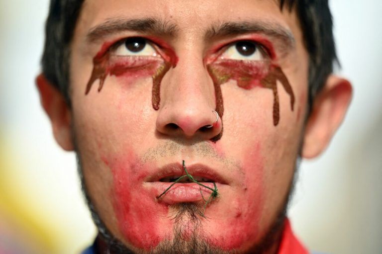 Ein junger Mann mit einem offenbar zugenähten Mund nimmt in Madrid an einem Protestmarsch mit dem Slogan „SOS Kolumbien“ teil. AFP