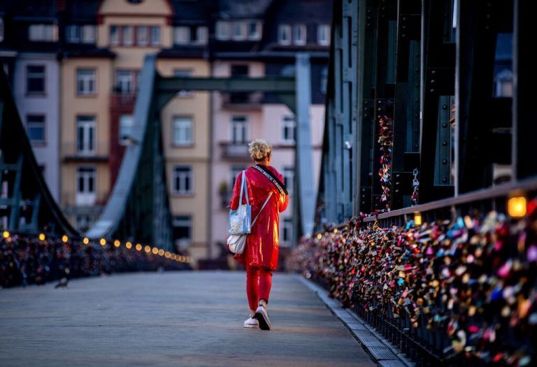 Eine Frau spaziert in Frankfurt am Main über eine Brücke, an der Pärchen unzählige 