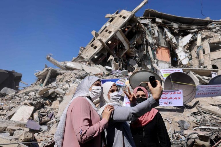 Palästinensische Frauen machen ein Selfie vor einem zerstörten Gebäude in Gaza-Stadt, das von israelischen Luftangriffen heimgesucht wurde.  AFP