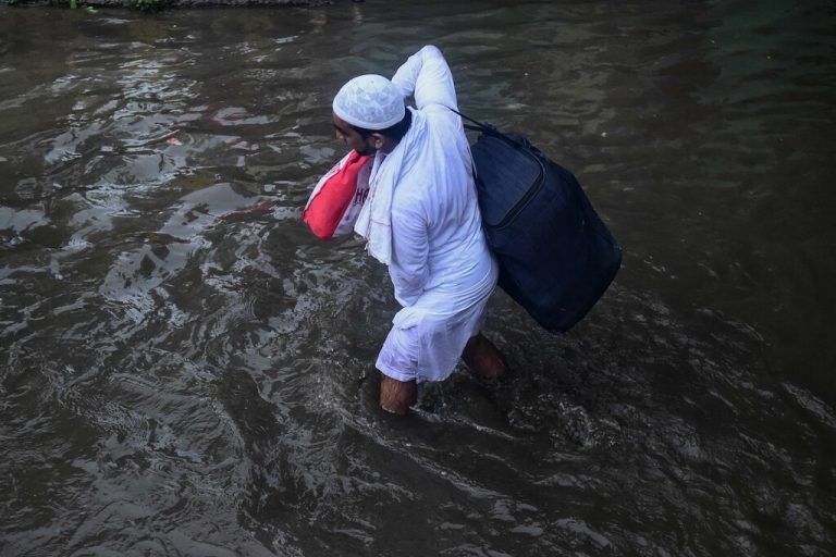 In der indischen Stadt Allahabad kämpft sich ein Mann mit seinem Gepäck durch eine vom Monsunregen überflutete Straße. AFP