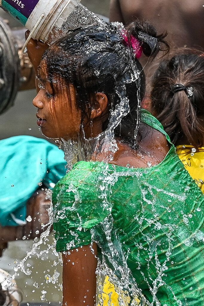 Mit kaltem Wasser aus einer Leitung kühlt sich ein junges Mädchen an einem heißen Sommertag im indischen Neu-Delhi ab. AFP