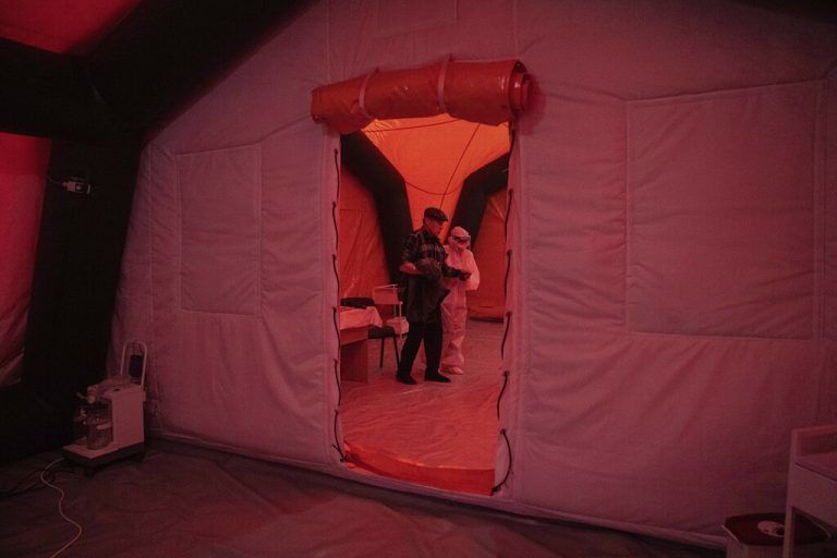 In einem Zeltspital bei Kakhovka in der Ukraine wird ein Covid-Patient von einem Gesundheitsmitarbeiter gestützt. AP