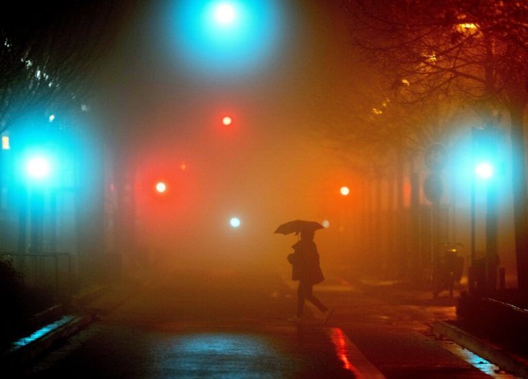 An einem verregneten und nebligen Morgen überquert ein Passant eine Straße in Frankfurt am Main. AP