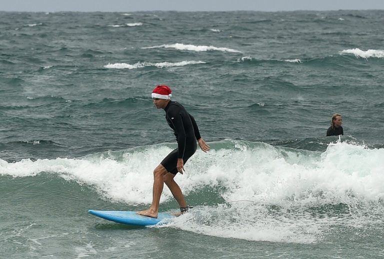 In Australien kann man surfende Santas beobachten. Noch mehr Weihnachtsmänner gibt es bei den „Santa Pub Crawls“ zu sehen, bei denen sich Kostümierte von Bar zu Bar trinken. AFP