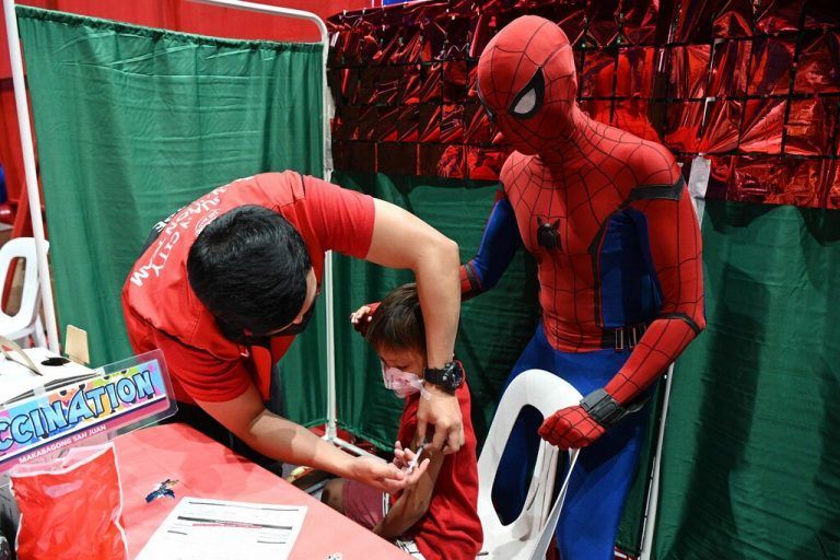Ein Spiderman-Darsteller spricht einem Kind, das im philippinischen Manila gegen Corona geimpft wird, Mut zu. AFP