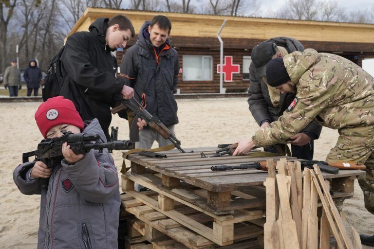 Während sich Erwachsene in Kiew Waffen erklären lassen, spielt ein Junge mit einer Kalaschnikow.AP