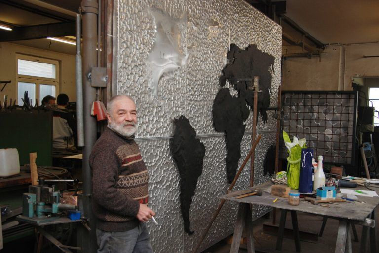 Wilfried „Wif“ Kofler vor seiner halbfertigen, aus einer Stahlplatte herausgetriebenen Weltkarte.<span class="copyright">hapf/2</span>