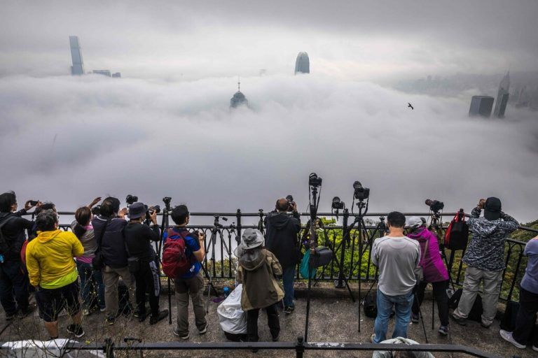 Auf einer Aussichtsplattform fotografieren Menschen die dichte Nebeldecke über Hongkong. AFP