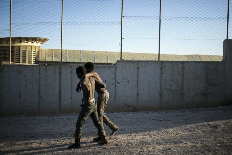Ein Migrant hilft einem anderen, nachdem sie die Zäune überwunden haben, die die spanische Enklave Melilla von Marokko trennen. AP