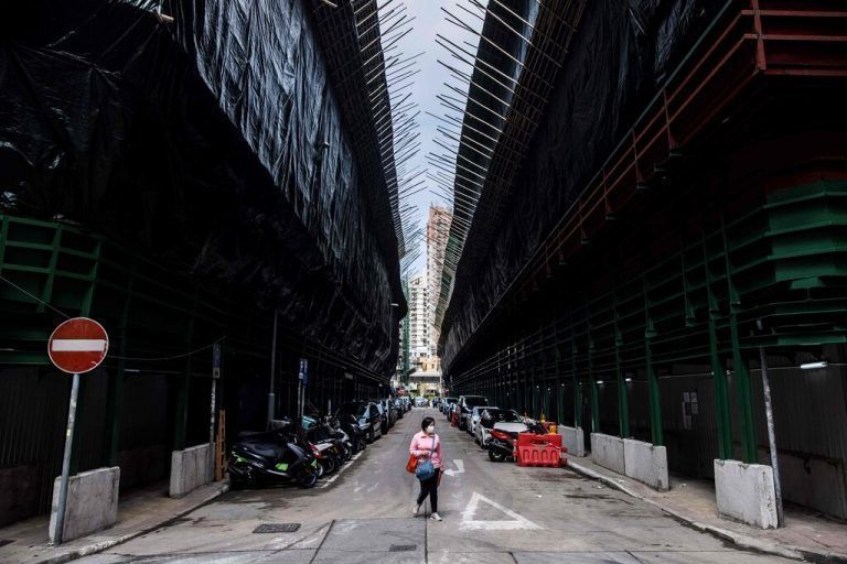 Eine Frau spaziert in Hongkong zwischen alten Wohngebäuden, die im Rahmen des Stadterneuerungsprojekts ersetzt werden. AFP