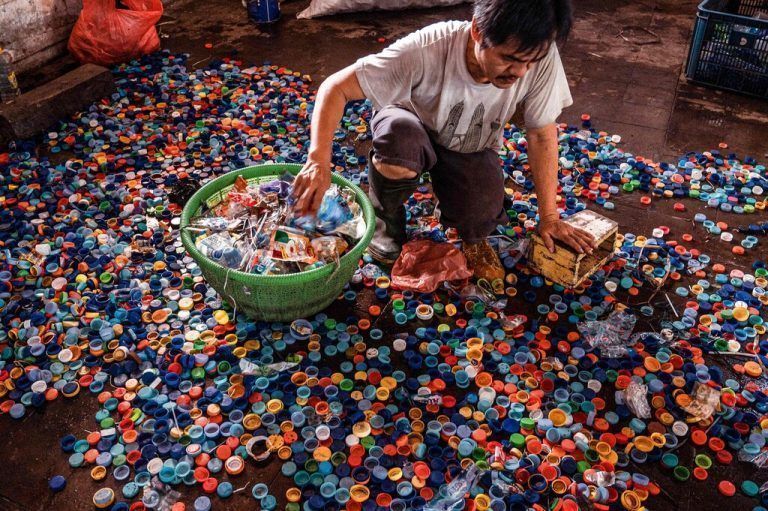 In Surabaya (Indonesien) wurden Flaschenverschlüsse gegen Bustickets gesammelt. Ein Arbeiter trennt sie von Müll, bevor er sie an Recyclingfabriken weiterverkauft. AFP