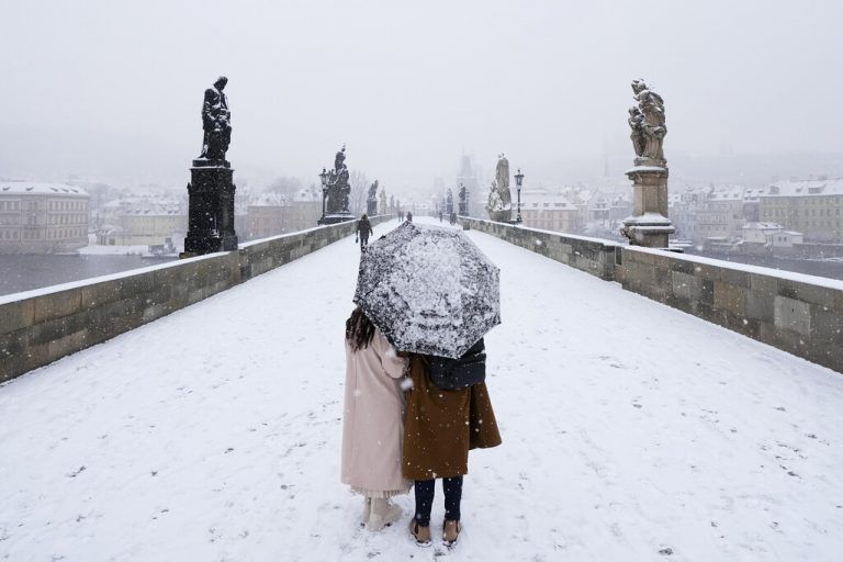 Während es schneit, spaziert ein Pärchen unter einem Regenschirm über die malerische Karlsbrücke in Prag, Tschechien. AP