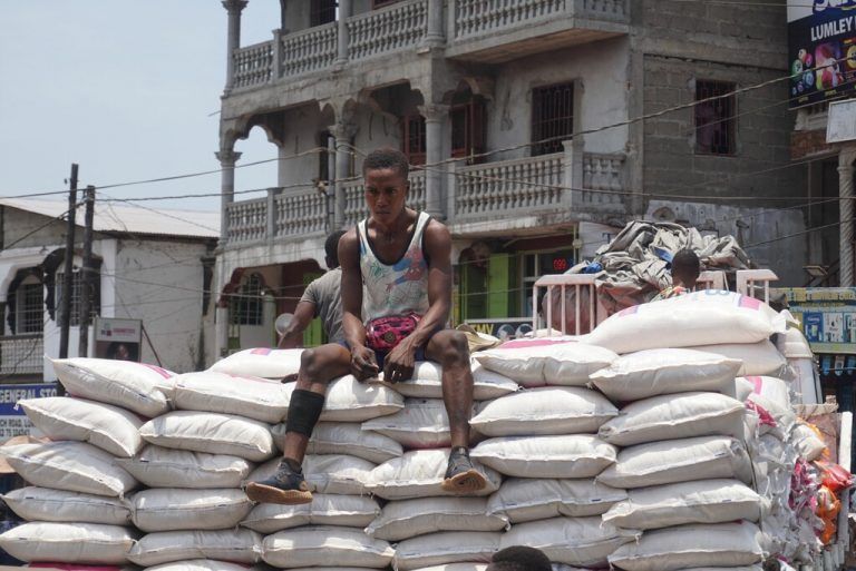 Ein Mann sitzt in Freetown, Sierra Leone, auf Reissäcken. Die gestiegenen Preise für Nahrung und Energie machen vielen Menschen zu schaffen. AFP