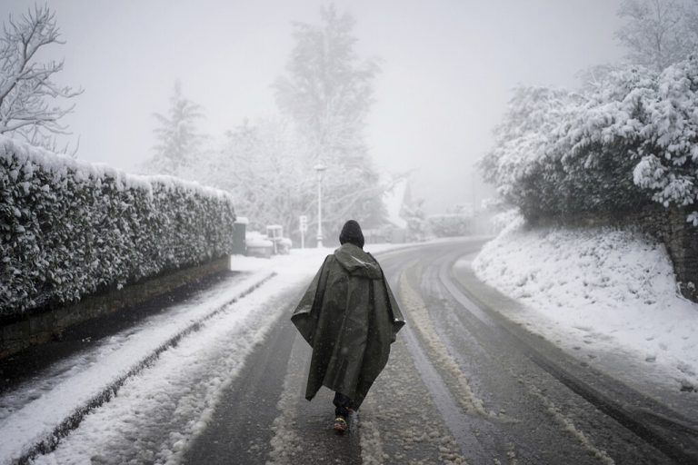 Ein Mensch läuft auf einer verschneiten Straße in Poleymieux au Mont d‘Or außerhalb der französischen Stadt Lyon. AP