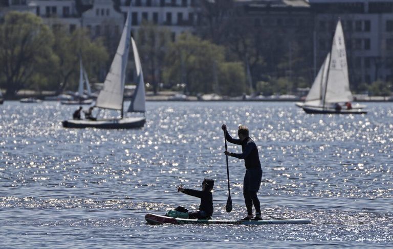 In Hamburg nutzen Ausflüger das warme Frühlingswetter und paddeln auf einem Surfboard über die Alster. AP