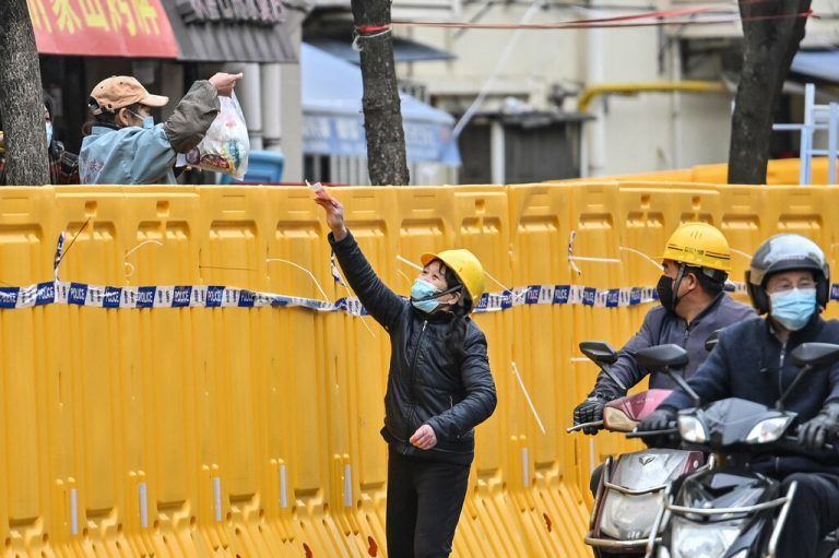 Lockdown in der Millionenmetropole Shanghai: Eine Frau aus einem abgeriegelten Viertel verkauft über eine Barriere hinweg Waren. AFP